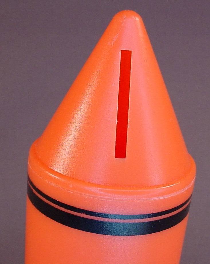 Orange Crayon Shaped Savings Bank With A Removable Bottom, 6 Inches Tall, Has A Coin Slot